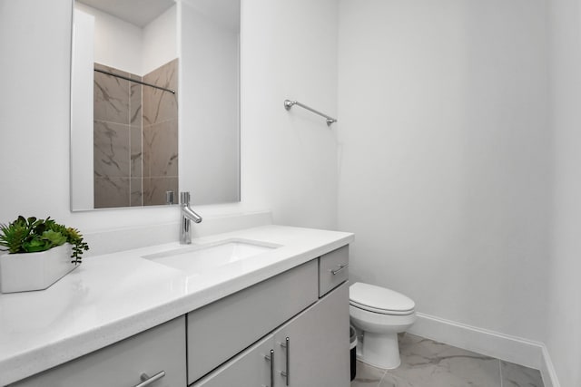 bathroom with a tile shower, vanity, and toilet