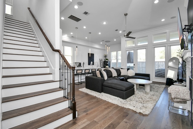 living room with dark wood-type flooring, a wealth of natural light, ceiling fan, and crown molding