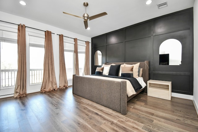 bedroom with dark hardwood / wood-style floors, ceiling fan, and multiple windows