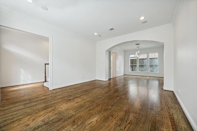 empty room featuring dark wood-type flooring, a chandelier, and crown molding