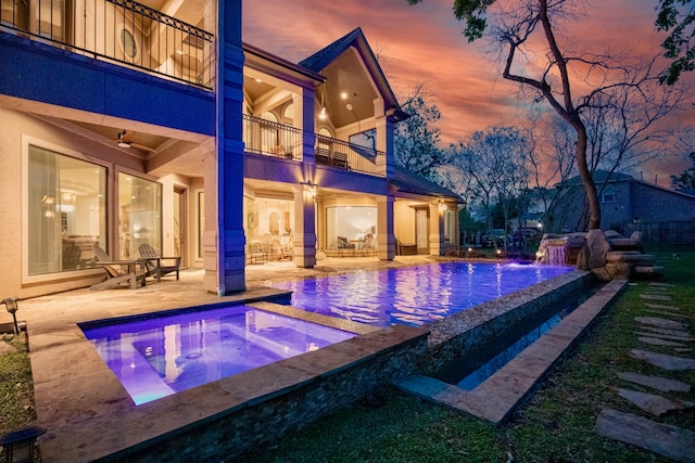 pool at dusk with a patio and an in ground hot tub