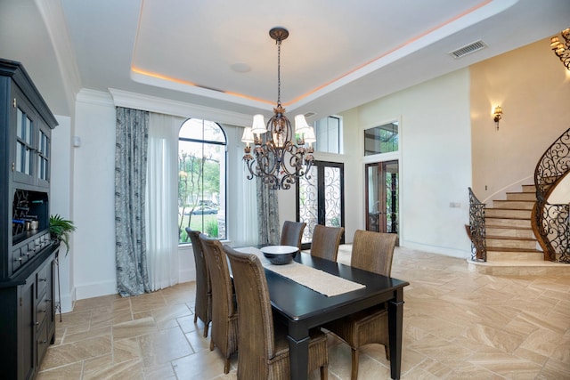 dining area featuring crown molding, a chandelier, and a raised ceiling