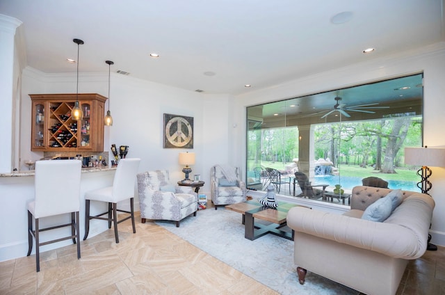 living room featuring ceiling fan, bar, and ornamental molding