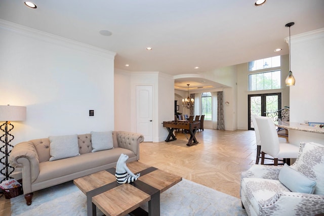 living room with light parquet flooring, an inviting chandelier, french doors, and crown molding