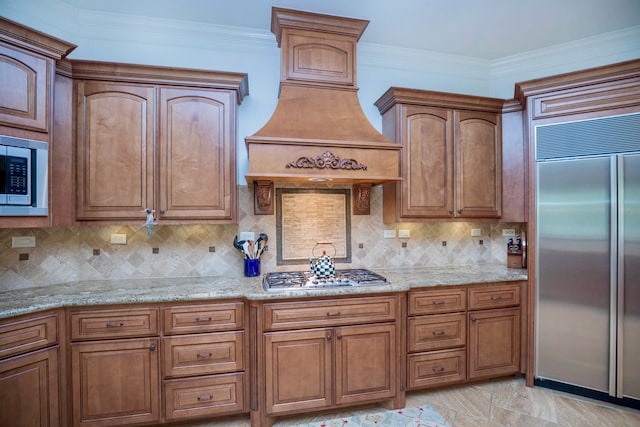 kitchen with built in appliances, ornamental molding, light stone counters, and tasteful backsplash