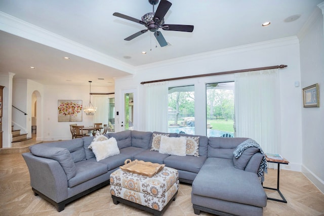 living room with ceiling fan with notable chandelier and crown molding