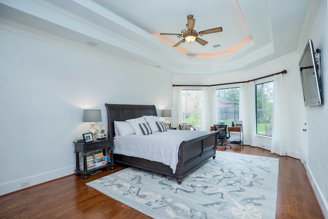 bedroom with ceiling fan, ornamental molding, dark hardwood / wood-style flooring, and a tray ceiling