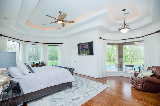 bedroom featuring a tray ceiling, wood-type flooring, and ceiling fan