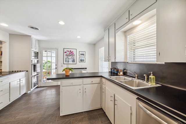 kitchen featuring sink, appliances with stainless steel finishes, kitchen peninsula, backsplash, and white cabinets