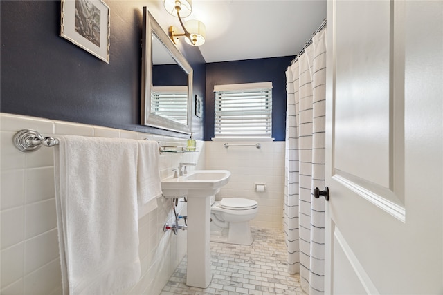 bathroom with tile walls, toilet, sink, and tile patterned floors