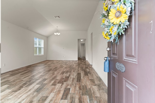 foyer with a chandelier, vaulted ceiling, and wood-type flooring