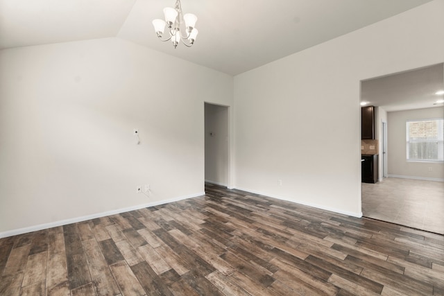 empty room featuring a chandelier, lofted ceiling, and dark hardwood / wood-style floors