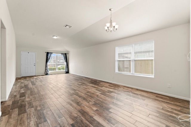 empty room featuring dark wood-type flooring, an inviting chandelier, and lofted ceiling