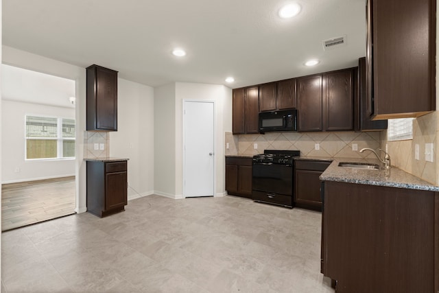 kitchen with dark brown cabinetry, light stone countertops, sink, and black appliances