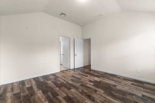 spare room with dark wood-type flooring and lofted ceiling