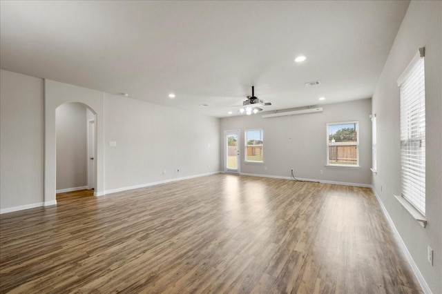 empty room with hardwood / wood-style flooring, ceiling fan, and a healthy amount of sunlight