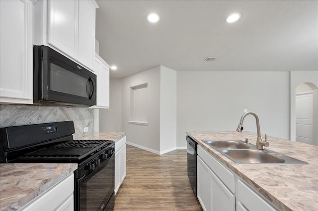 kitchen featuring decorative backsplash, sink, black appliances, white cabinets, and light hardwood / wood-style floors