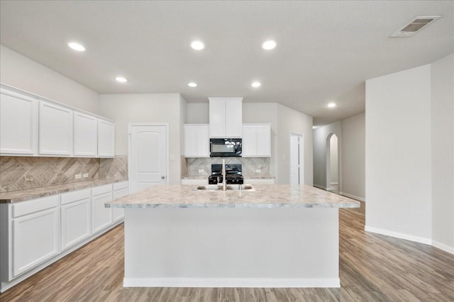 kitchen featuring black appliances, a center island with sink, white cabinets, sink, and light wood-type flooring