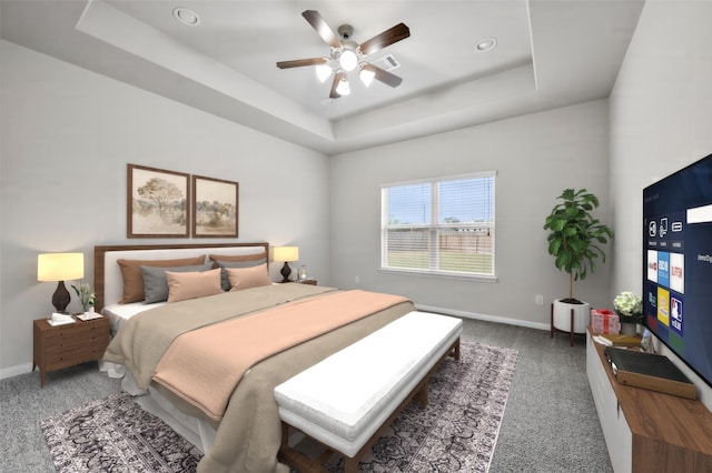 carpeted bedroom featuring ceiling fan and a tray ceiling