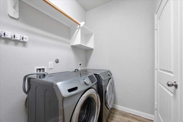 clothes washing area with washer and clothes dryer and hardwood / wood-style flooring