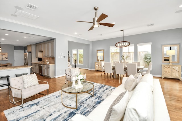 living room with hardwood / wood-style floors and ceiling fan with notable chandelier