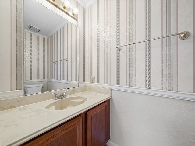 bathroom with vanity, toilet, and crown molding