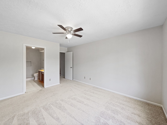 unfurnished bedroom with a textured ceiling, ensuite bath, light carpet, and ceiling fan