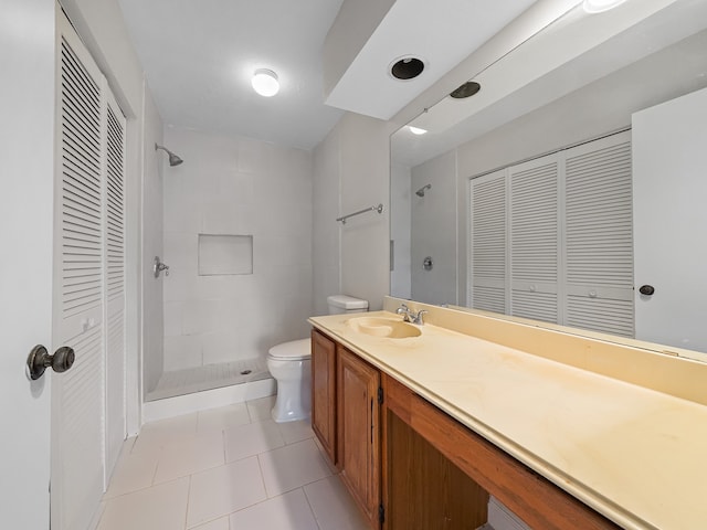 bathroom featuring vanity, tile patterned floors, toilet, and a tile shower