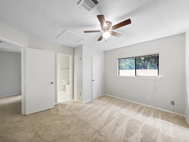 unfurnished bedroom with connected bathroom, a textured ceiling, light carpet, and ceiling fan