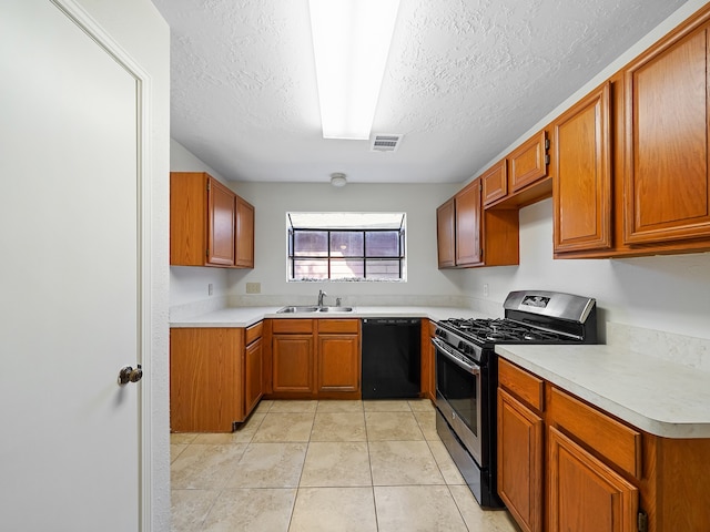 kitchen with stainless steel range with gas stovetop, sink, a textured ceiling, light tile patterned floors, and black dishwasher