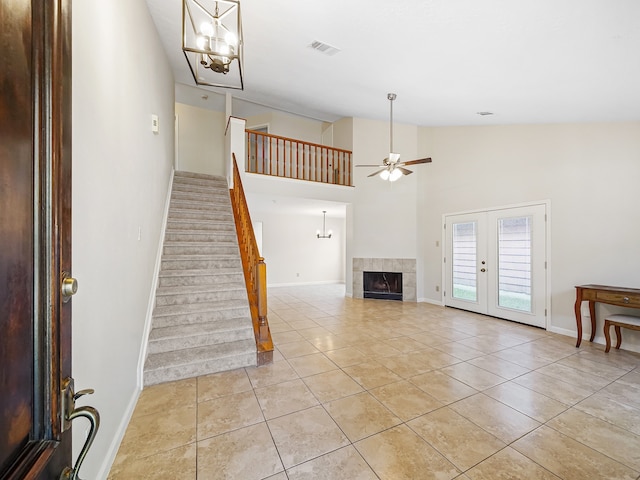 unfurnished living room with ceiling fan, high vaulted ceiling, light tile patterned floors, and french doors