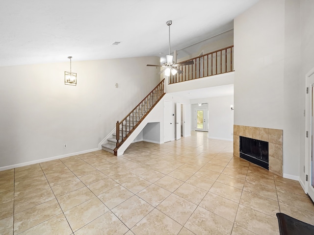 unfurnished living room with high vaulted ceiling, a tiled fireplace, light tile patterned floors, and ceiling fan