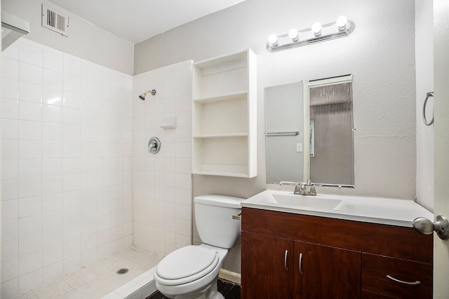 bathroom with toilet, vanity, and a tile shower