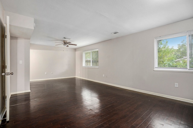 spare room featuring ceiling fan, a wealth of natural light, a textured ceiling, and dark hardwood / wood-style floors