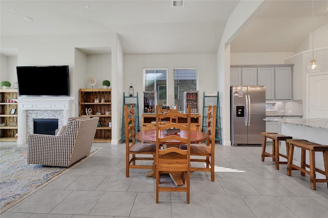 dining area with a fireplace, lofted ceiling, and light tile patterned floors