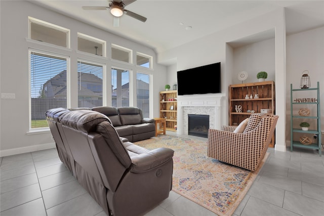 tiled living room featuring a fireplace and ceiling fan