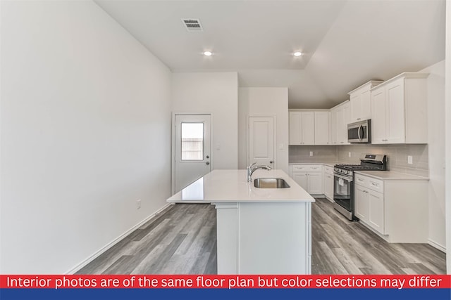 kitchen featuring white cabinetry, appliances with stainless steel finishes, light wood-type flooring, sink, and an island with sink