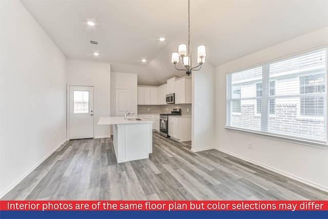 kitchen featuring white cabinetry, appliances with stainless steel finishes, an island with sink, light hardwood / wood-style flooring, and lofted ceiling