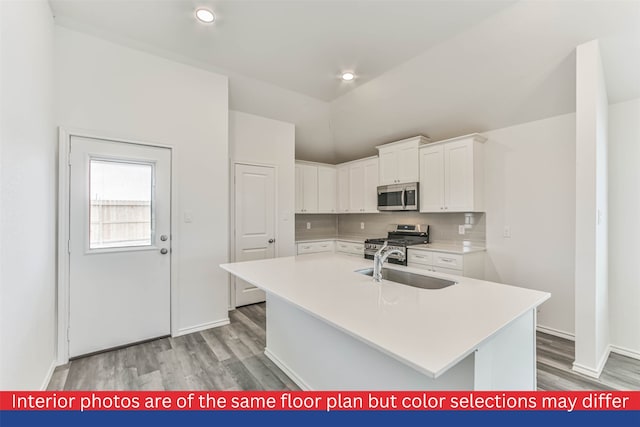 kitchen featuring light wood-type flooring, white cabinetry, appliances with stainless steel finishes, and a kitchen island with sink