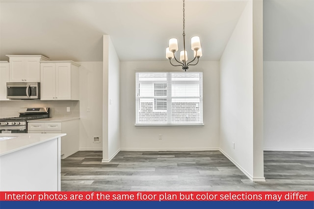 kitchen with stainless steel appliances, white cabinets, hardwood / wood-style flooring, a chandelier, and backsplash