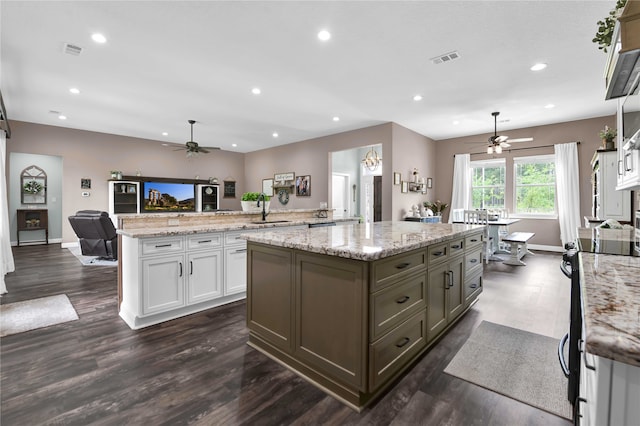 kitchen featuring a kitchen island, white cabinetry, light stone countertops, and dark hardwood / wood-style floors