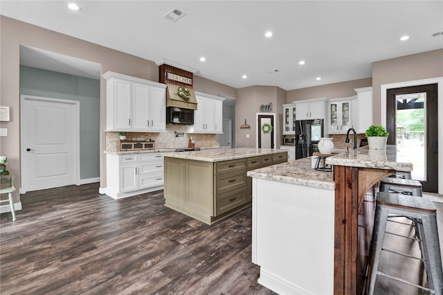 kitchen with white cabinetry, black appliances, dark hardwood / wood-style floors, and a kitchen island