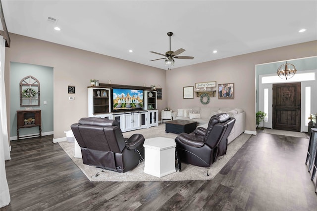 living room with ceiling fan with notable chandelier and dark hardwood / wood-style flooring