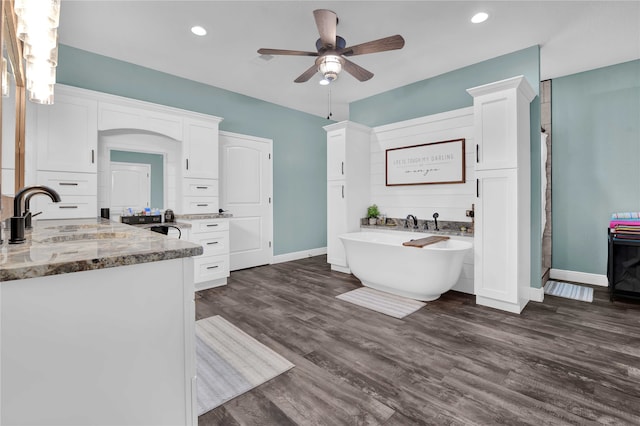 bathroom featuring ceiling fan, hardwood / wood-style flooring, a tub to relax in, and vanity