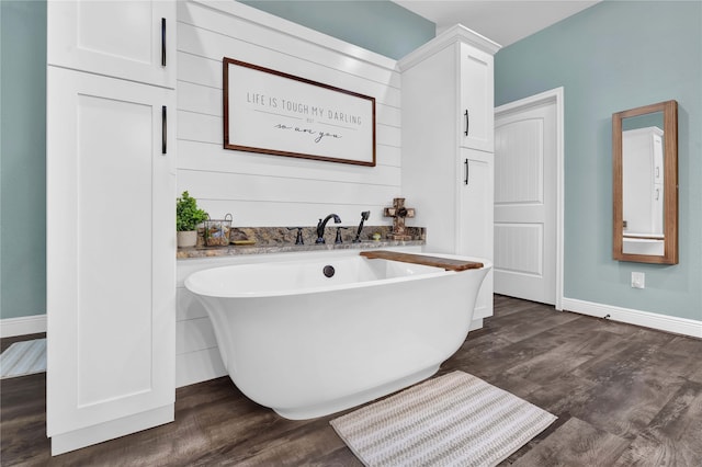 bathroom with hardwood / wood-style flooring and a tub to relax in