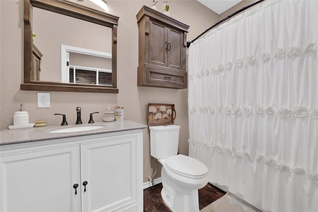 bathroom with hardwood / wood-style flooring, vanity, toilet, and walk in shower