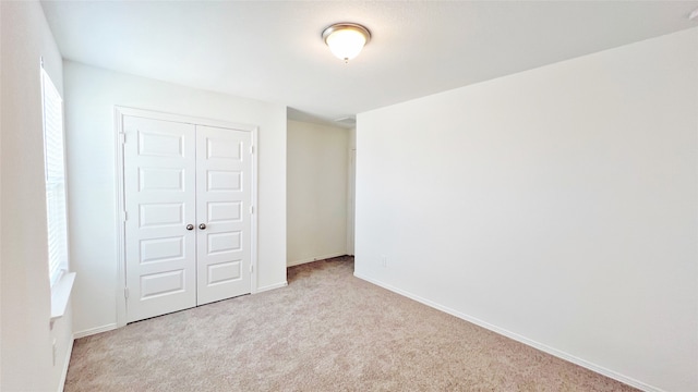 unfurnished bedroom featuring a closet and light carpet