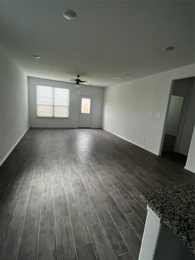 unfurnished living room featuring ceiling fan and dark hardwood / wood-style floors