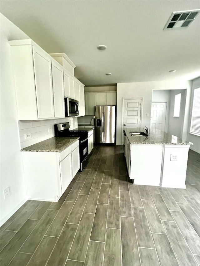 kitchen with dark wood-type flooring, white cabinetry, sink, and appliances with stainless steel finishes