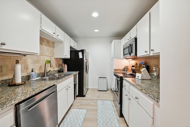 kitchen featuring dark stone countertops, white cabinetry, appliances with stainless steel finishes, and light wood-type flooring